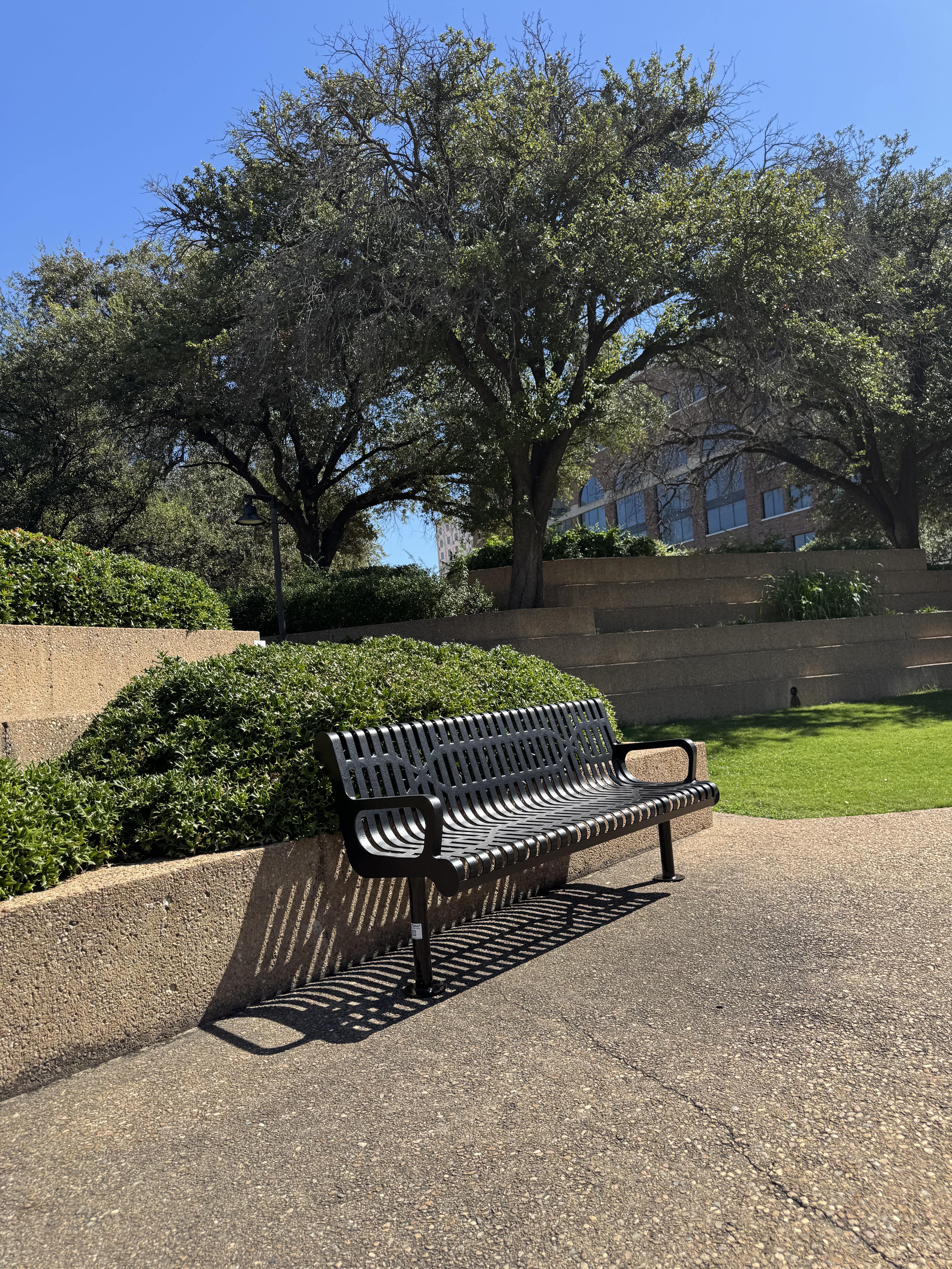 Black MyTCoat Contoured Bench Slatted Steel Lifestyle Image with Bush Garden Background and Surface Mount