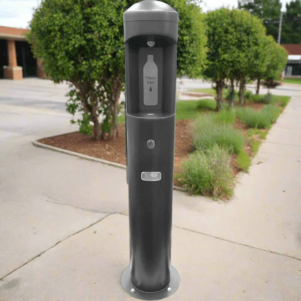 Gray Willoughy Outdoor Water Bottle Filling Station standard unit on a sidewalk with trees and building in the background