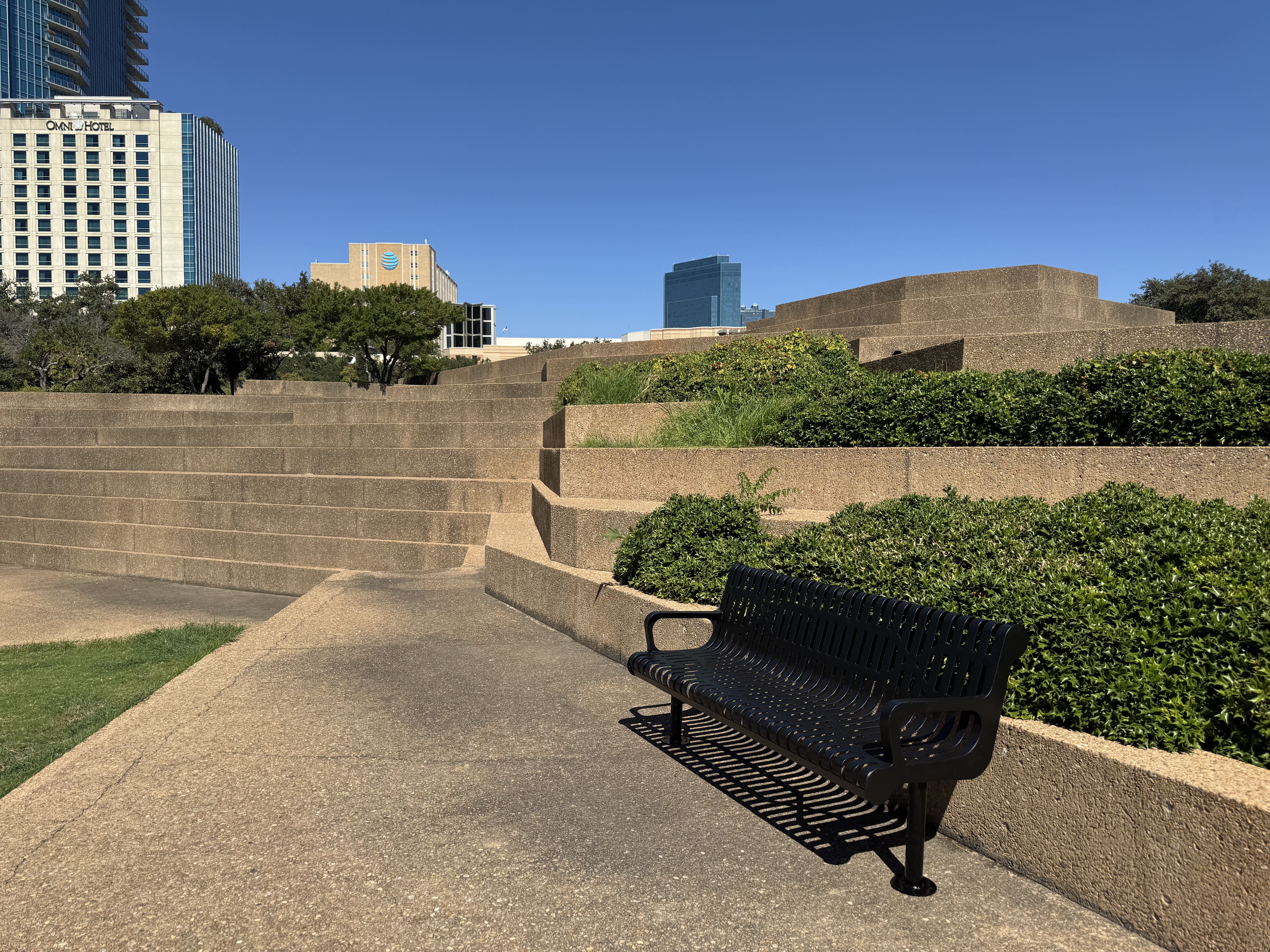 Multiple Black MyTCoat Contoured Bench Slatted Steel Surface Mount Lifestyle Image with City Background