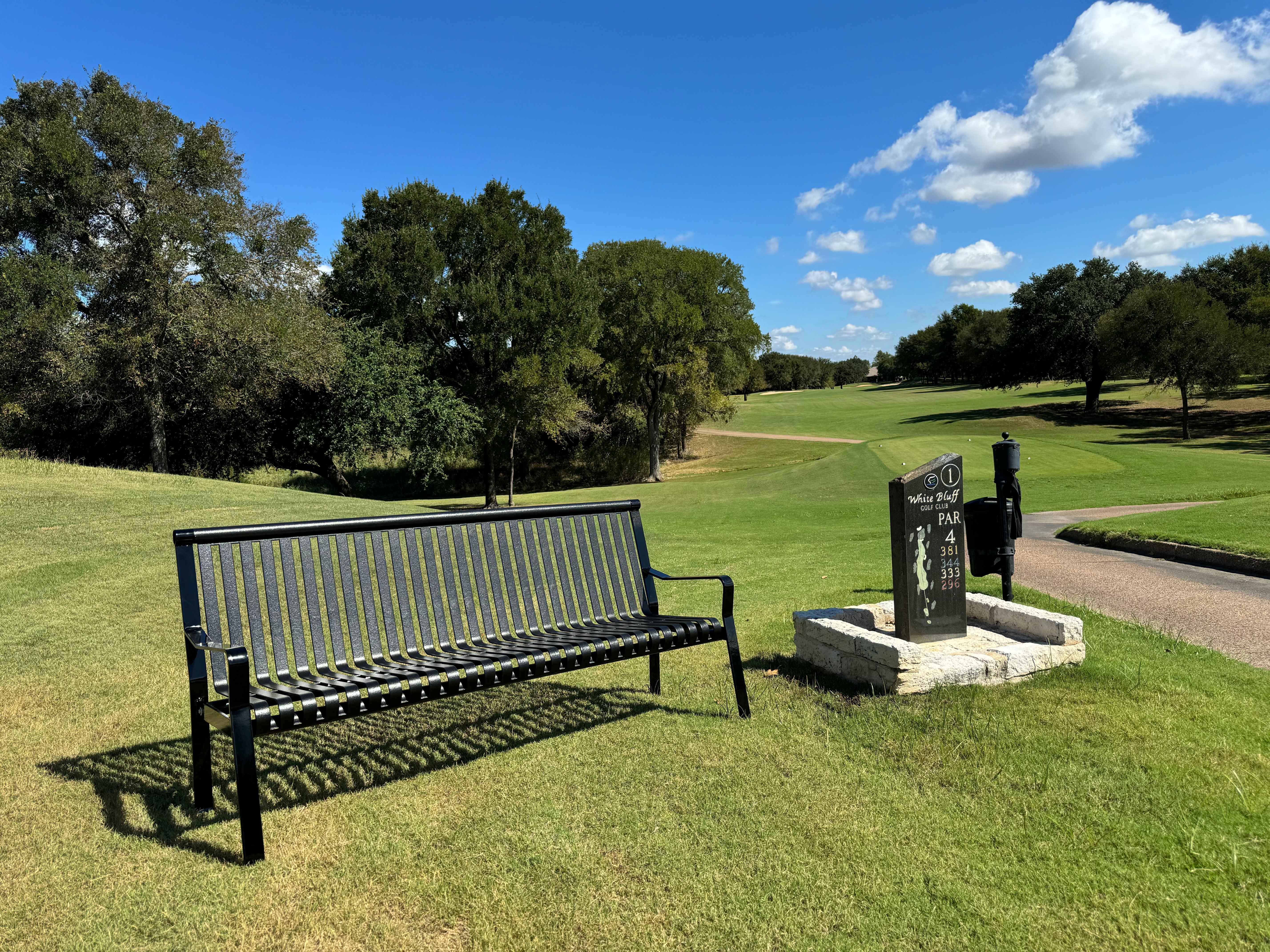MyTCoat Metal Downtown Park Bench with Back Lifestyle Image with Golf Course Par 4 Background