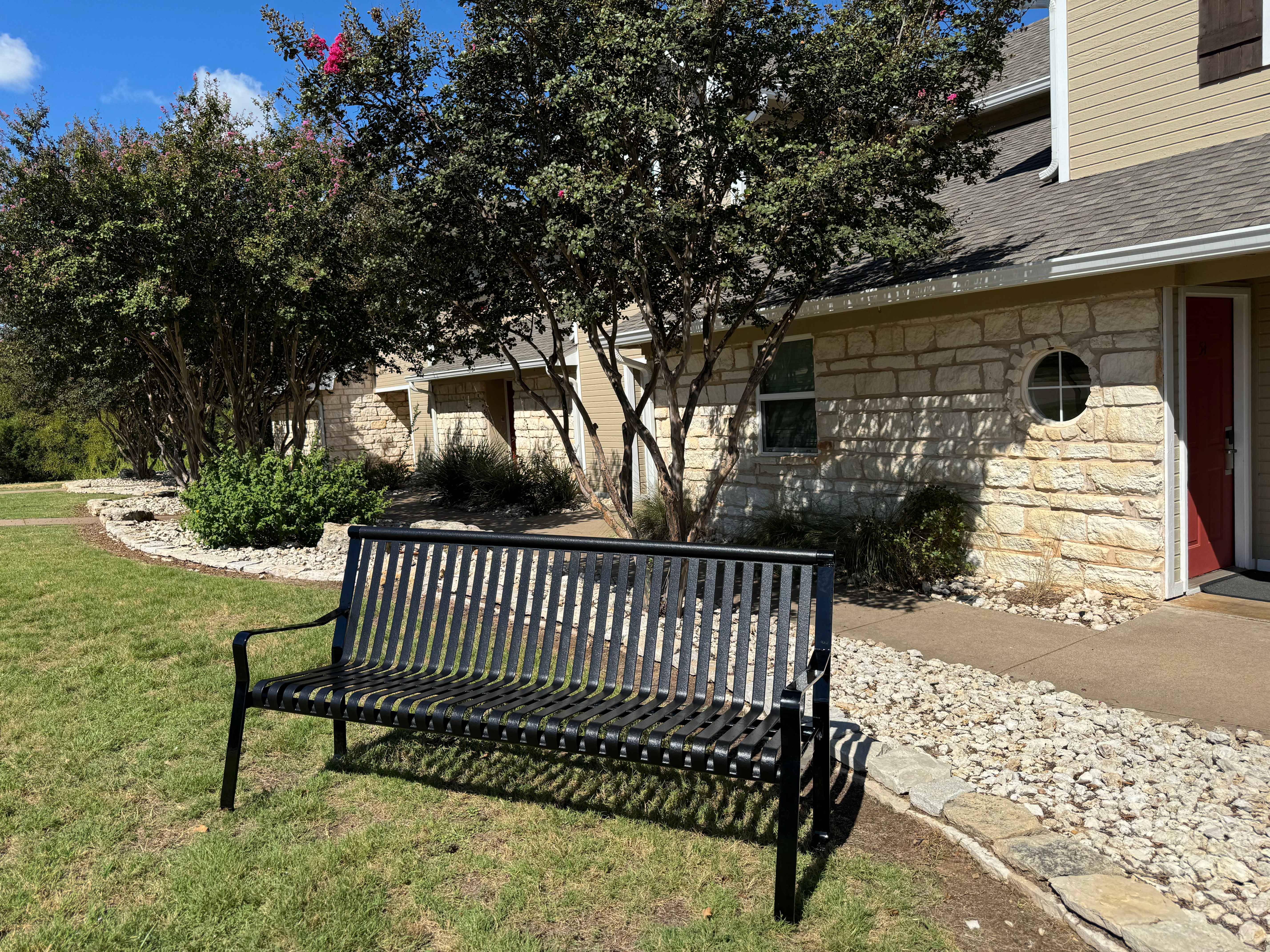 MyTCoat Metal Downtown Park Bench with Back Lifestyle Image with House Front Yard Background