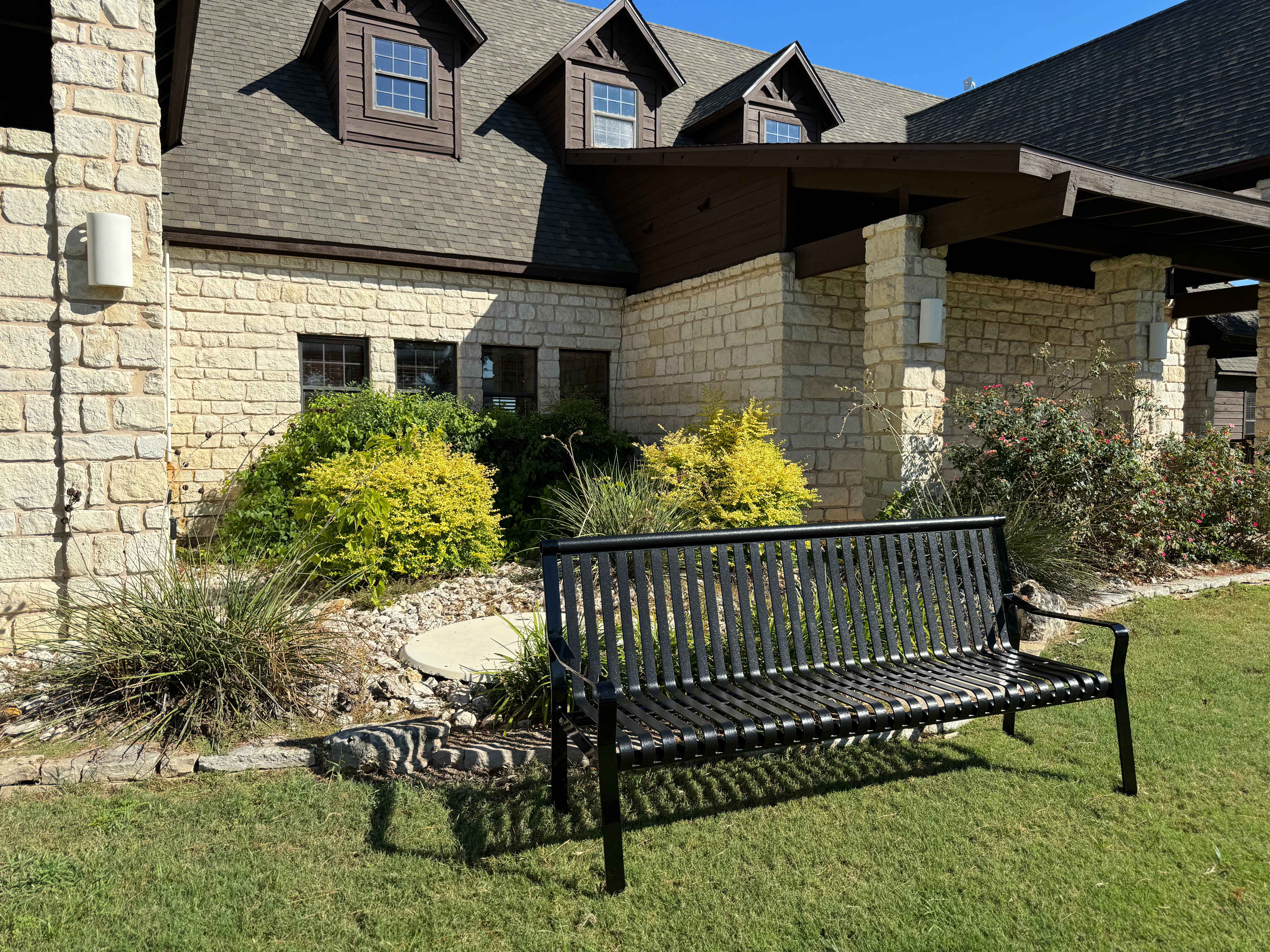 MyTCoat Metal Downtown Park Bench with Back Lifestyle Image with Upscale House Background