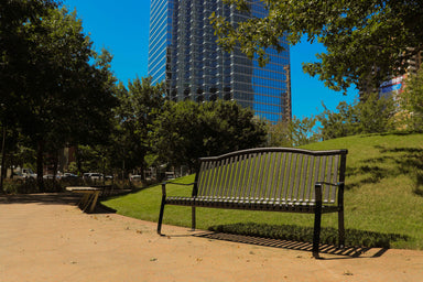 MyTCoat Metal Park Skyline Bench Lifestyle Image with Park and Building Background