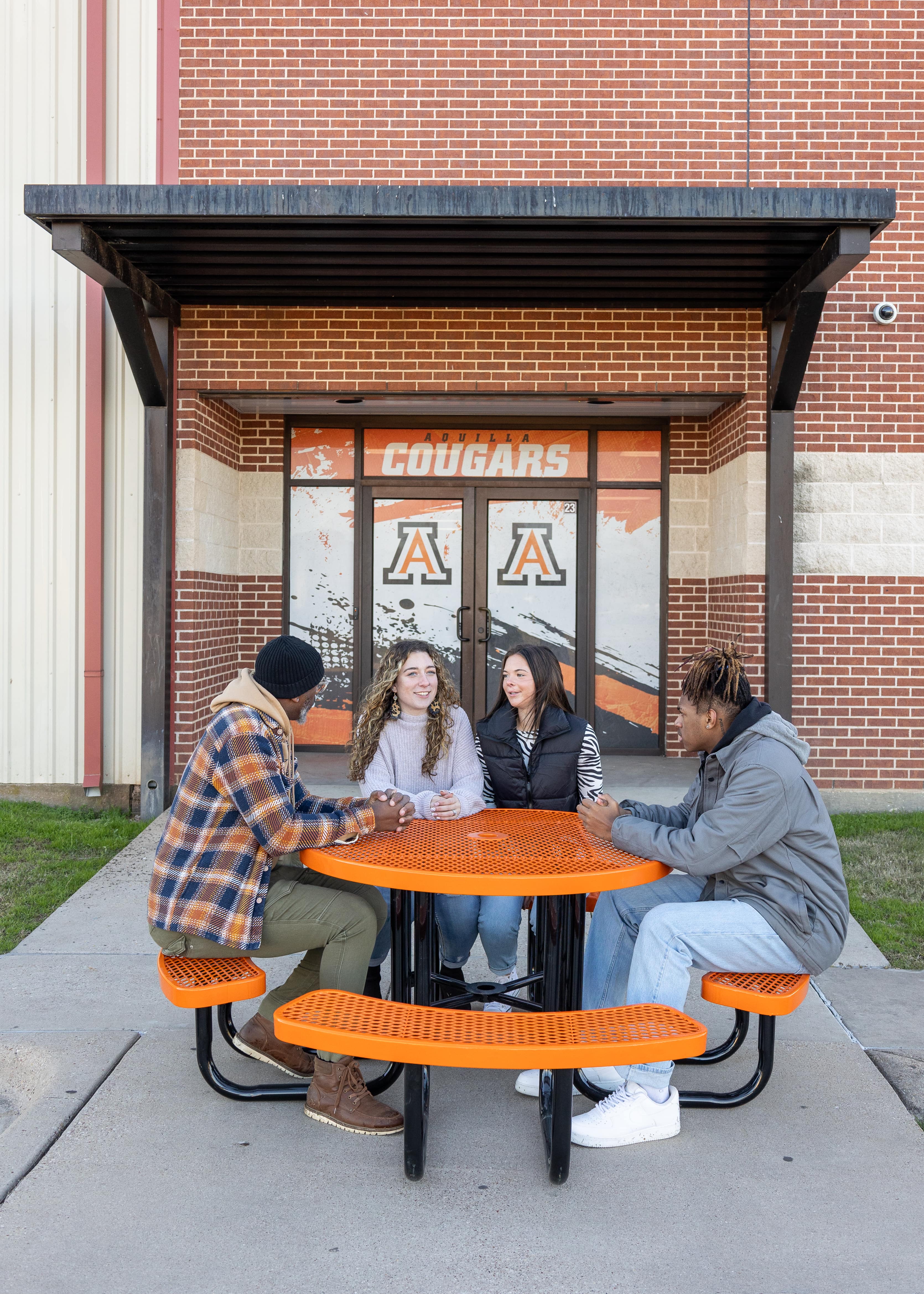 Orange MyTCoat Round Portable Picnic Table Lifestyle Image in School Courtyard and People Sitting