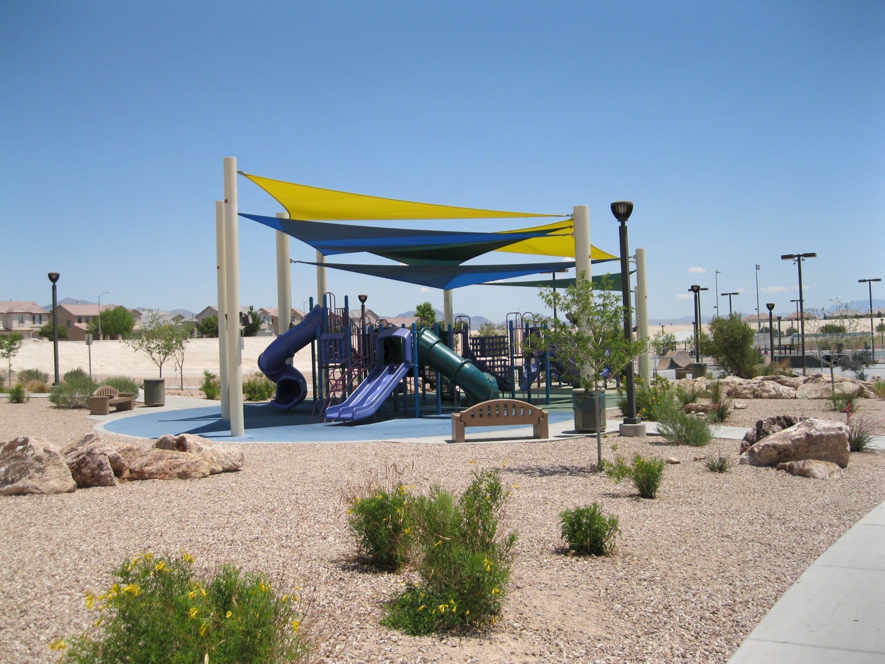 Sail shade canopies over a children's playground with slides
