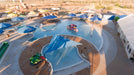 Aerial view of a large outdoor pool area with blue USA Shade Coolbrellas and a pool toy.