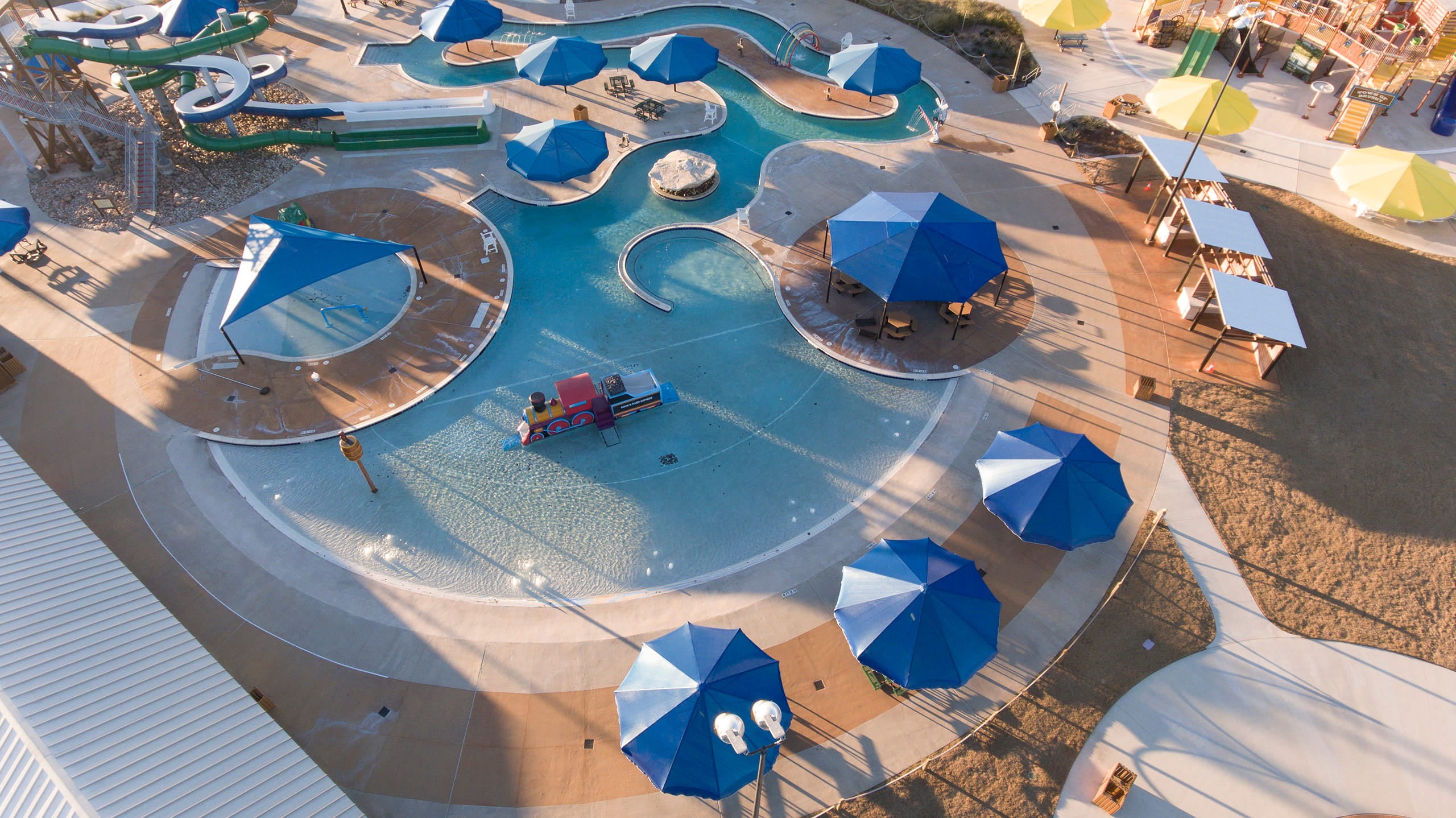 Outdoor pool area with blue USA Shade Coolbrellas and lounge chairs on a sunny day.