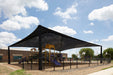 Black USA Shade Super Span Hip over a playground with a blue sky and clouds in the background