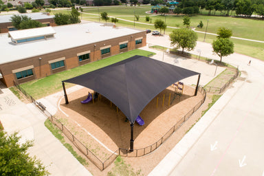 Large black USA Shade Super Span Hip over a playground area in an outdoor setting with a building and trees in the background.