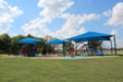 Children's playground with blue USA Shade Hips and slides under a clear blue sky.