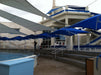Blue and white building with large blue USA Shade Single Post Cantilever Shade Structure on a cloudy day