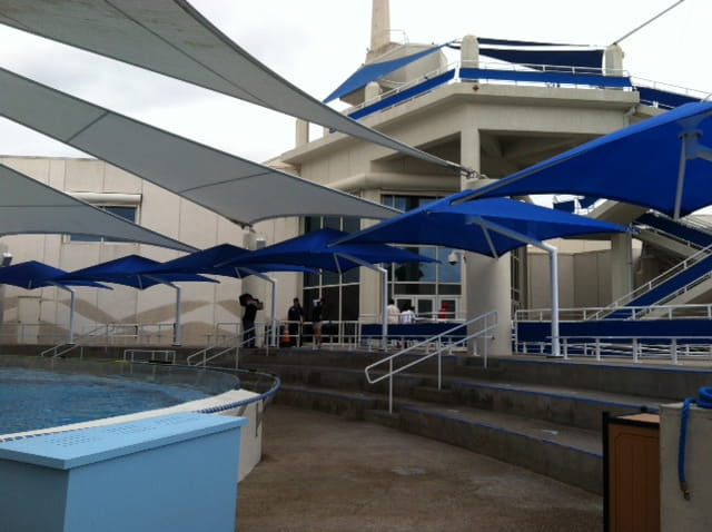 Blue and white building with large blue USA Shade Single Post Cantilever Shade Structure on a cloudy day