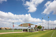 USA Shade Panorama Cantilever Covered area on a sports field with a clear blue sky and white clouds.