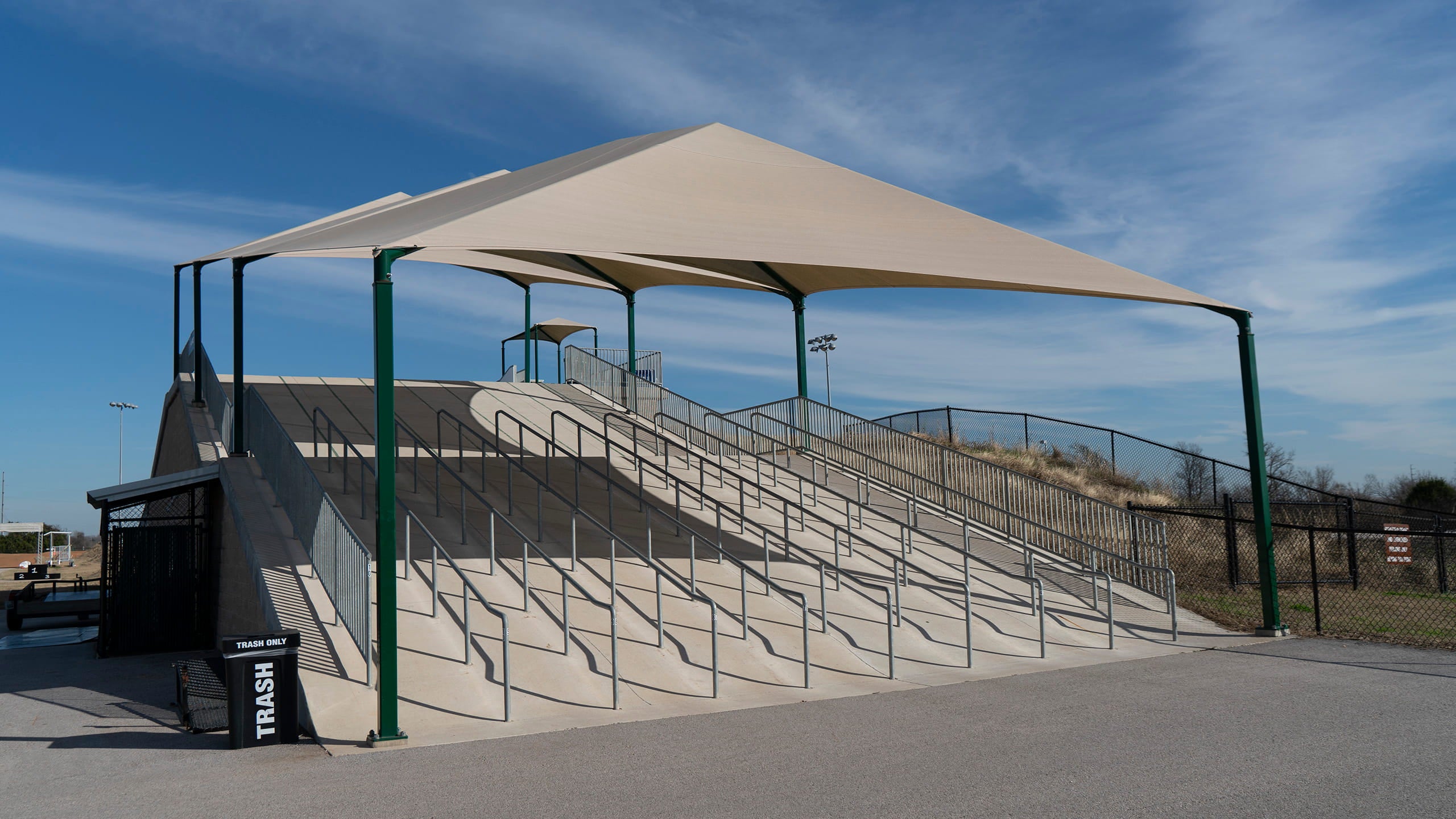 Covered walkway with stairs leading up to a building vovered by USA Shade Hip Canopies under a clear blue sky.