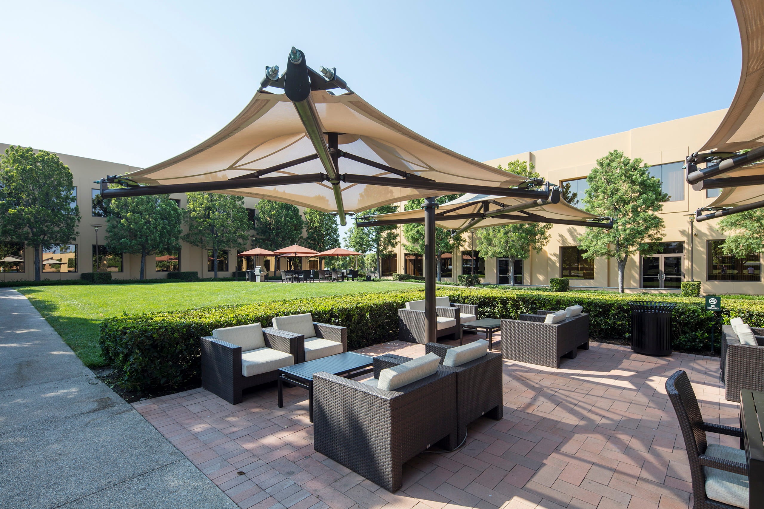 Outdoor patio area with furniture and umbrellas under large USA Shade Solana Cantilevers.