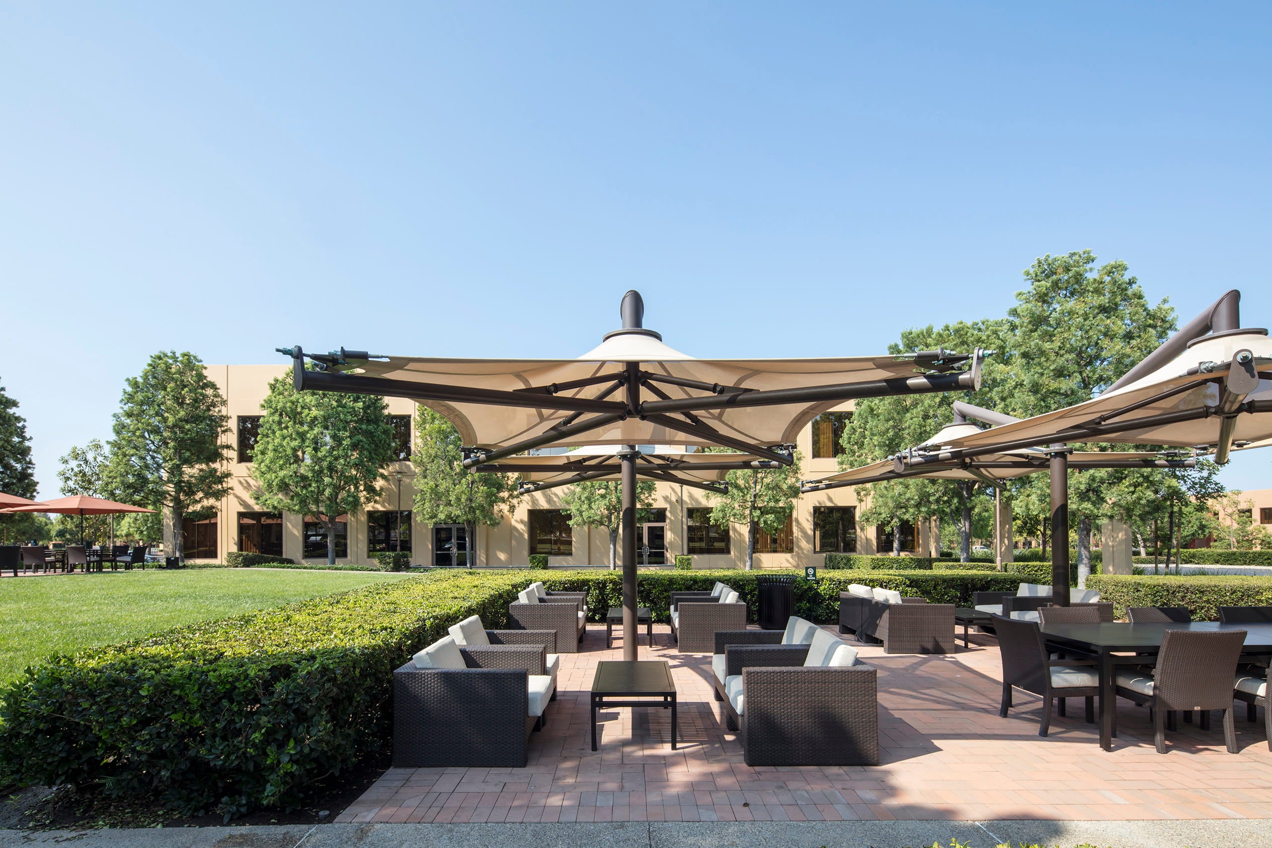 Outdoor seating area with tables and chairs under large USA Shade Solana Cantilevers on a sunny day.