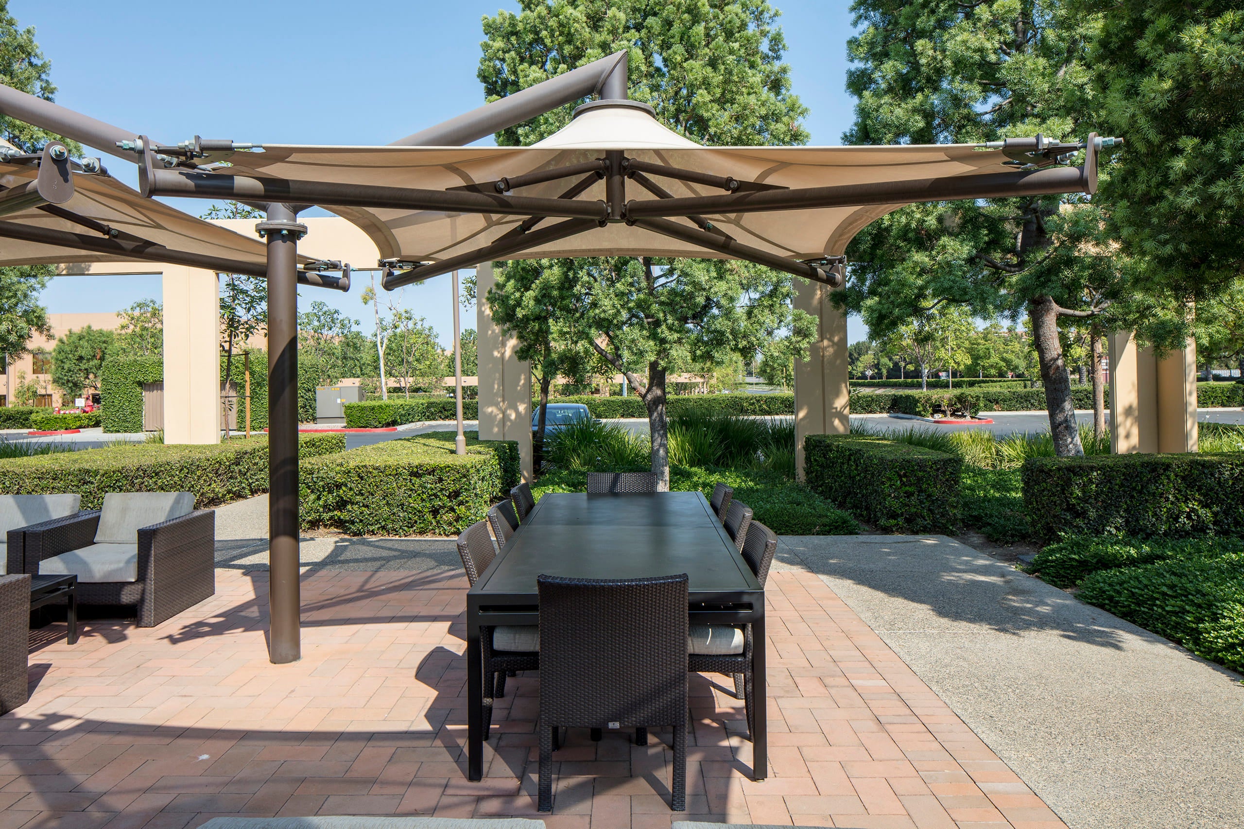 Outdoor patio with large USA Shade Solana Cantilevers, dining table, and chairs in a park-like setting.