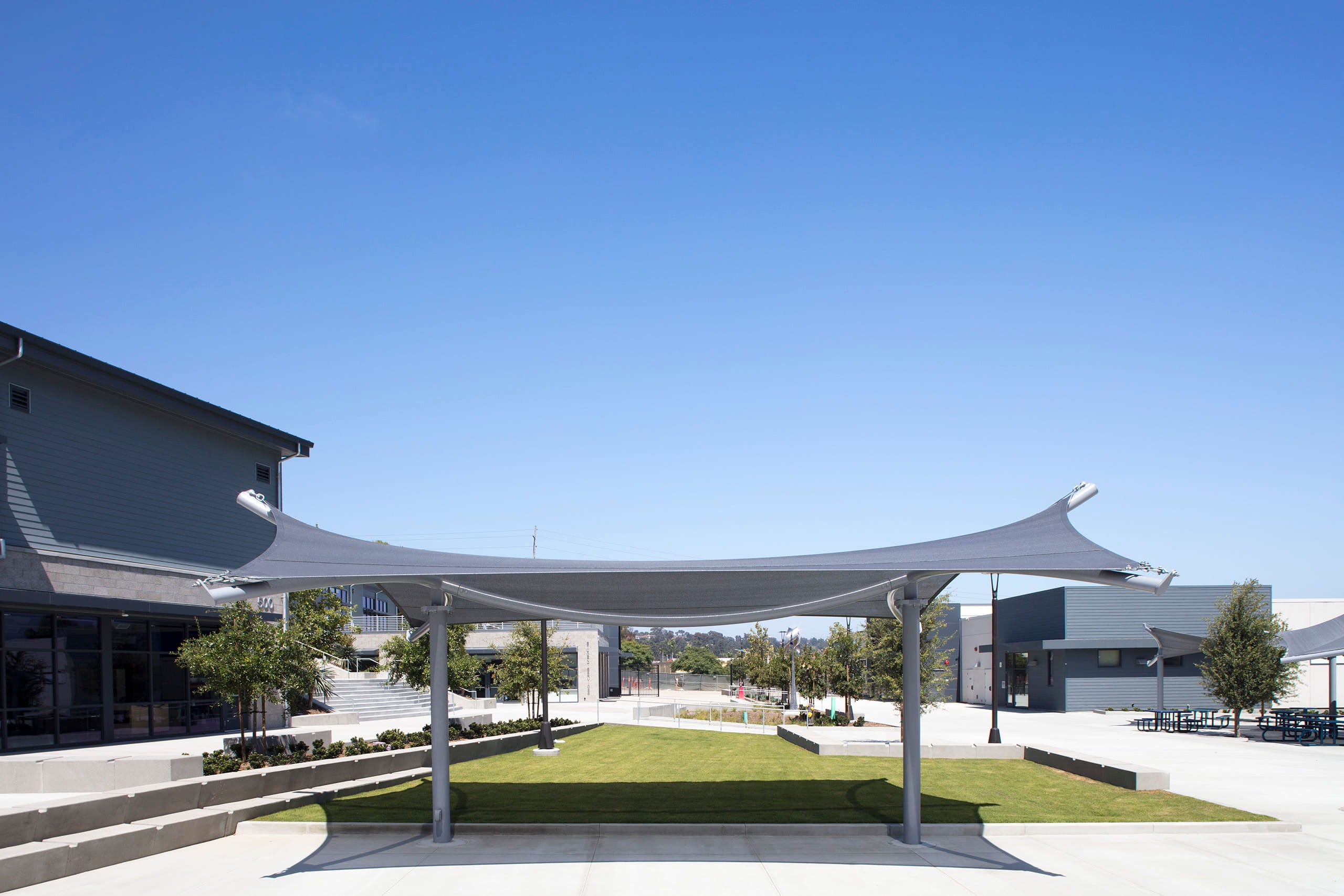 Outdoor USA Shade Aquarius Shade covered area with green grass and trees under a clear blue sky