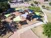 Aerial view of a playground with colorful USA Shade Arbor Shade structures and a path leading to it.