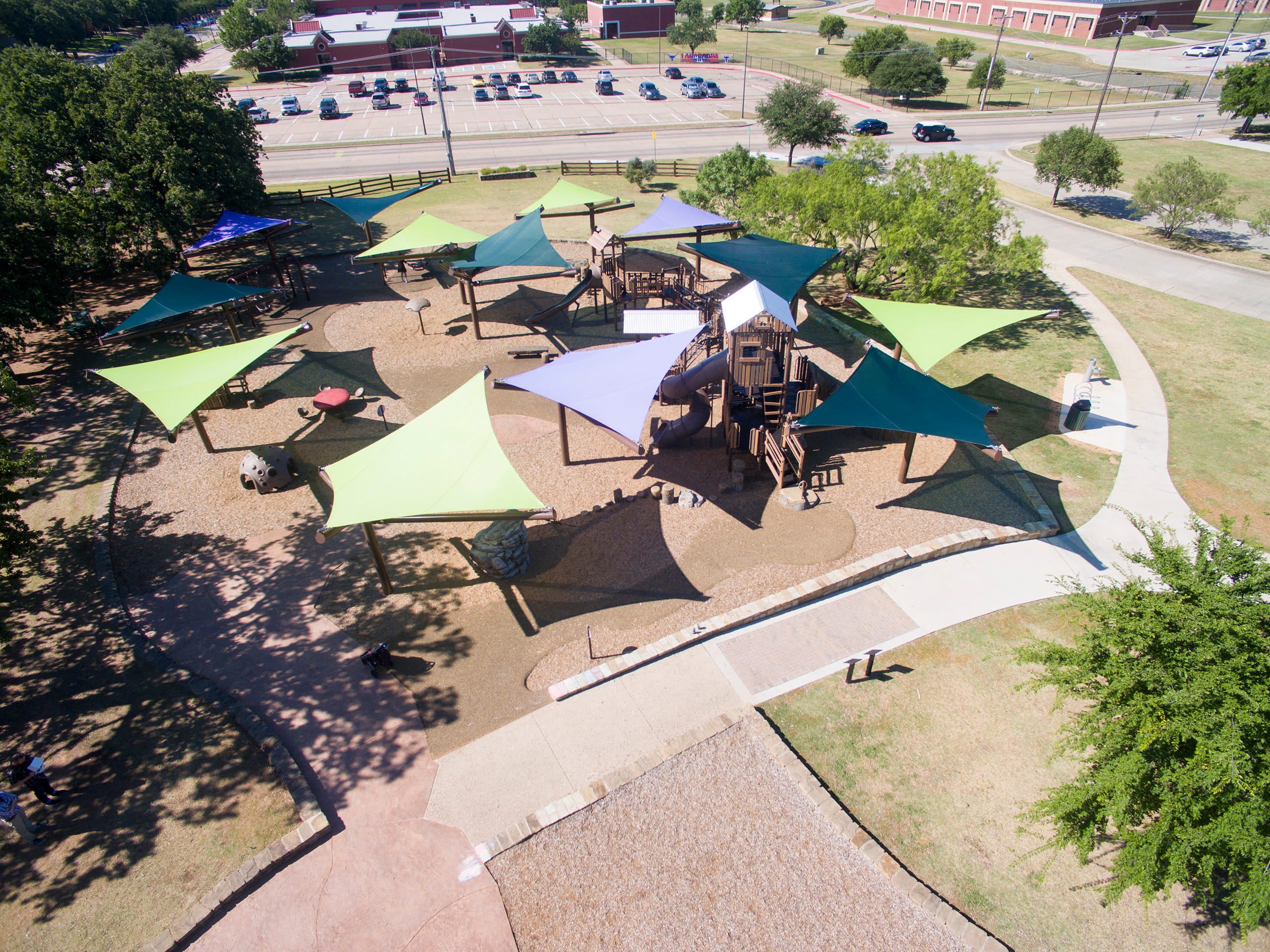 Aerial view of a playground with colorful USA Shade Arbor Shade structures and a path leading to it.