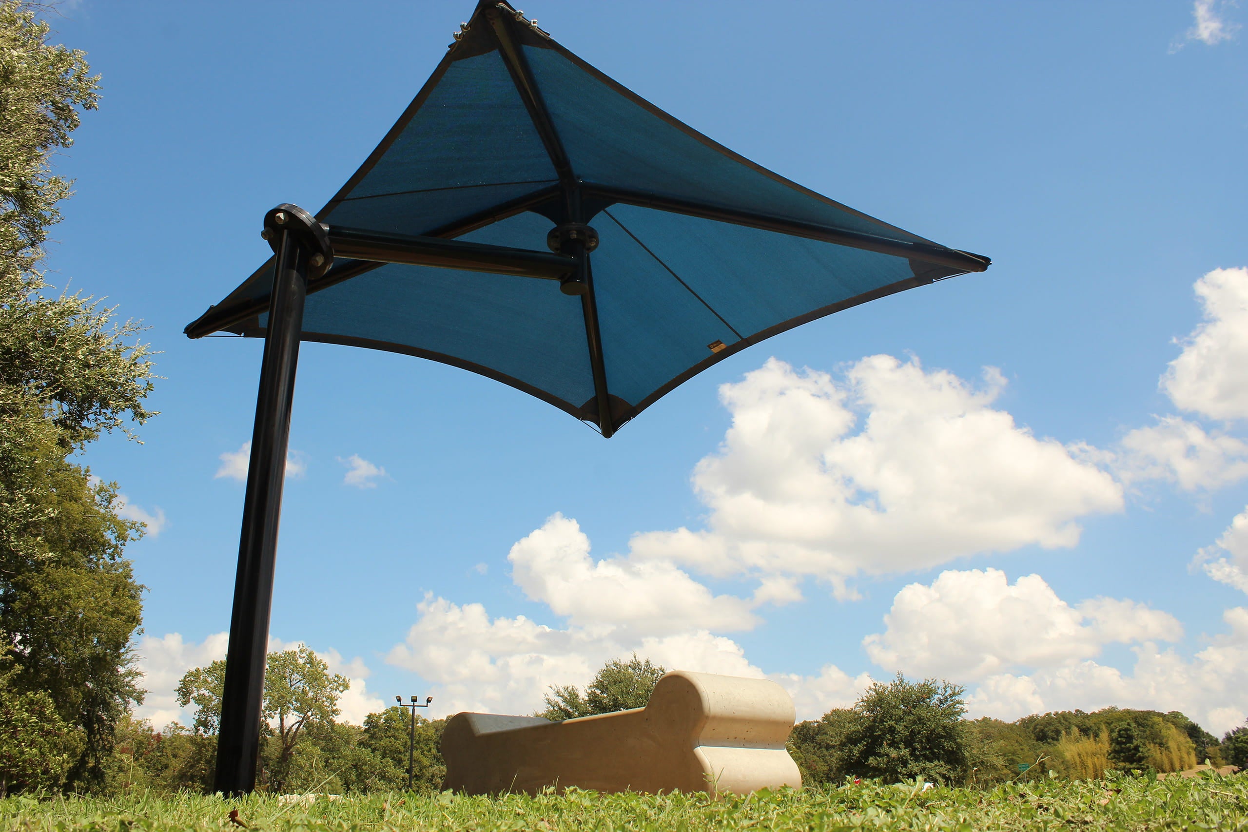 Blue USA Shade Single Post Cantilever Shade Structure on a stand against a blue sky with clouds Bottom Angle