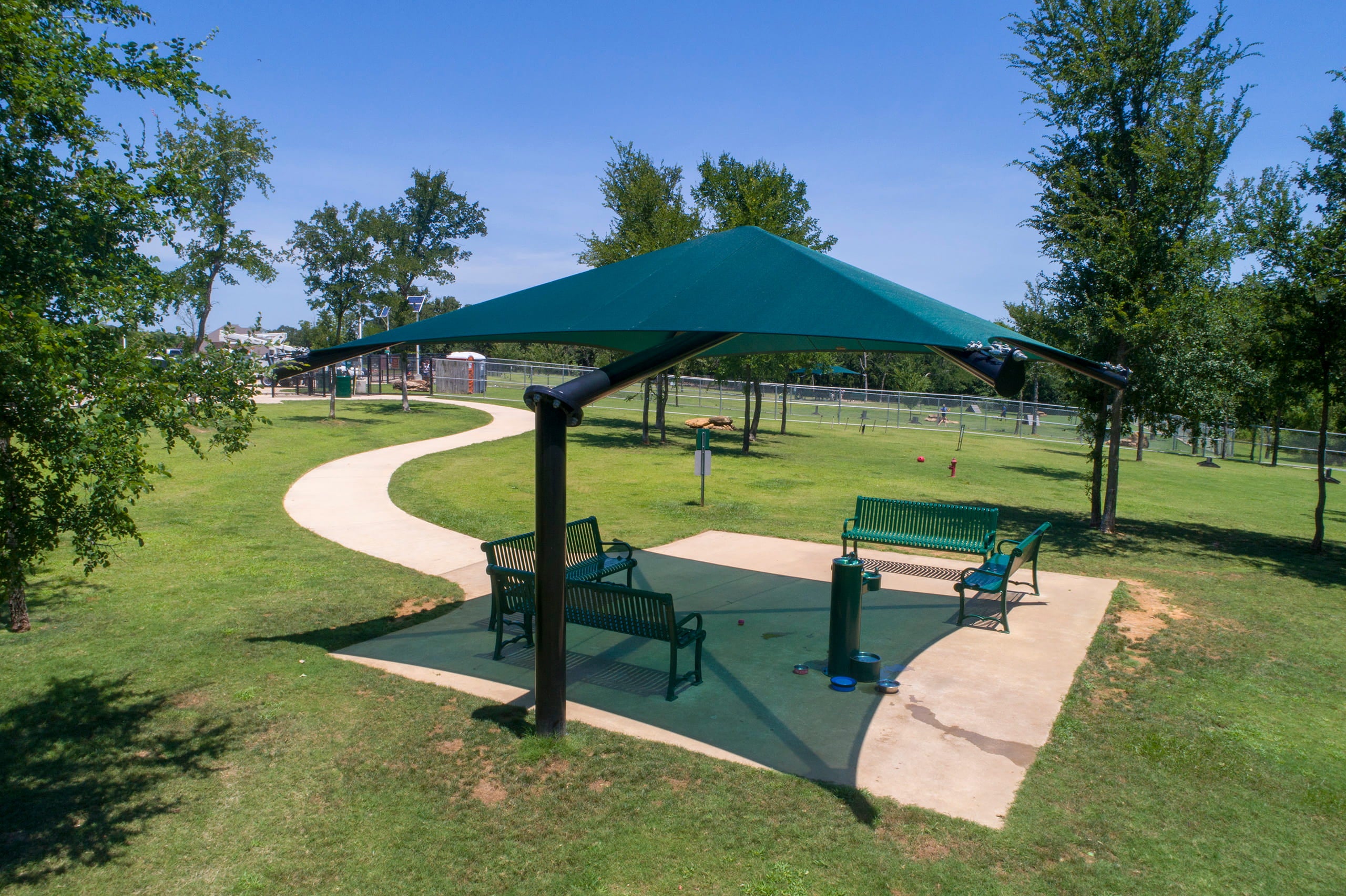 Green USA Shade Single Post Cantilever Shade Structure in a park with benches and trees
