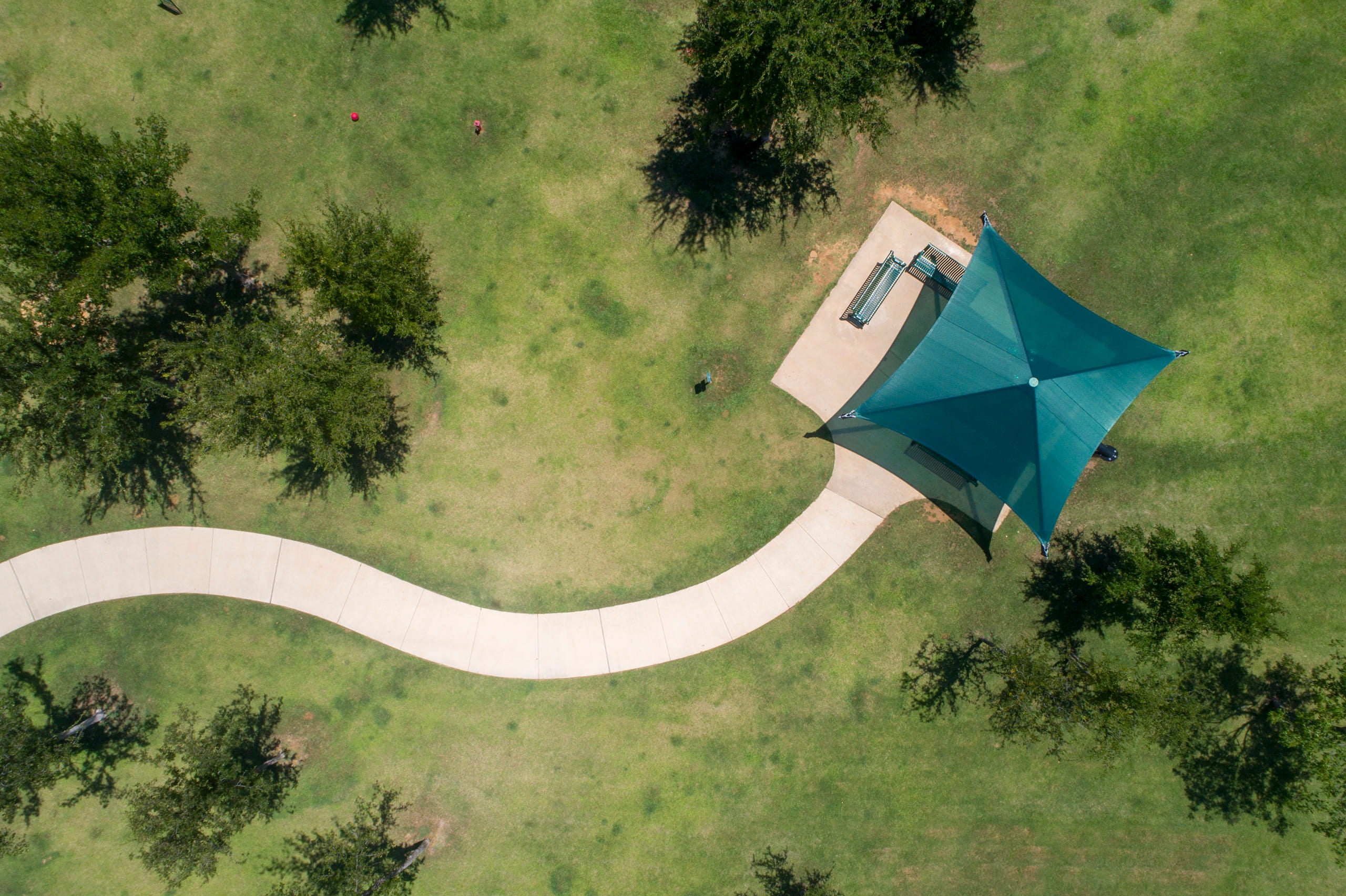 green USA Shade Single Post Cantilever Shade Structure on a grassy area with trees and a path Birds eye View