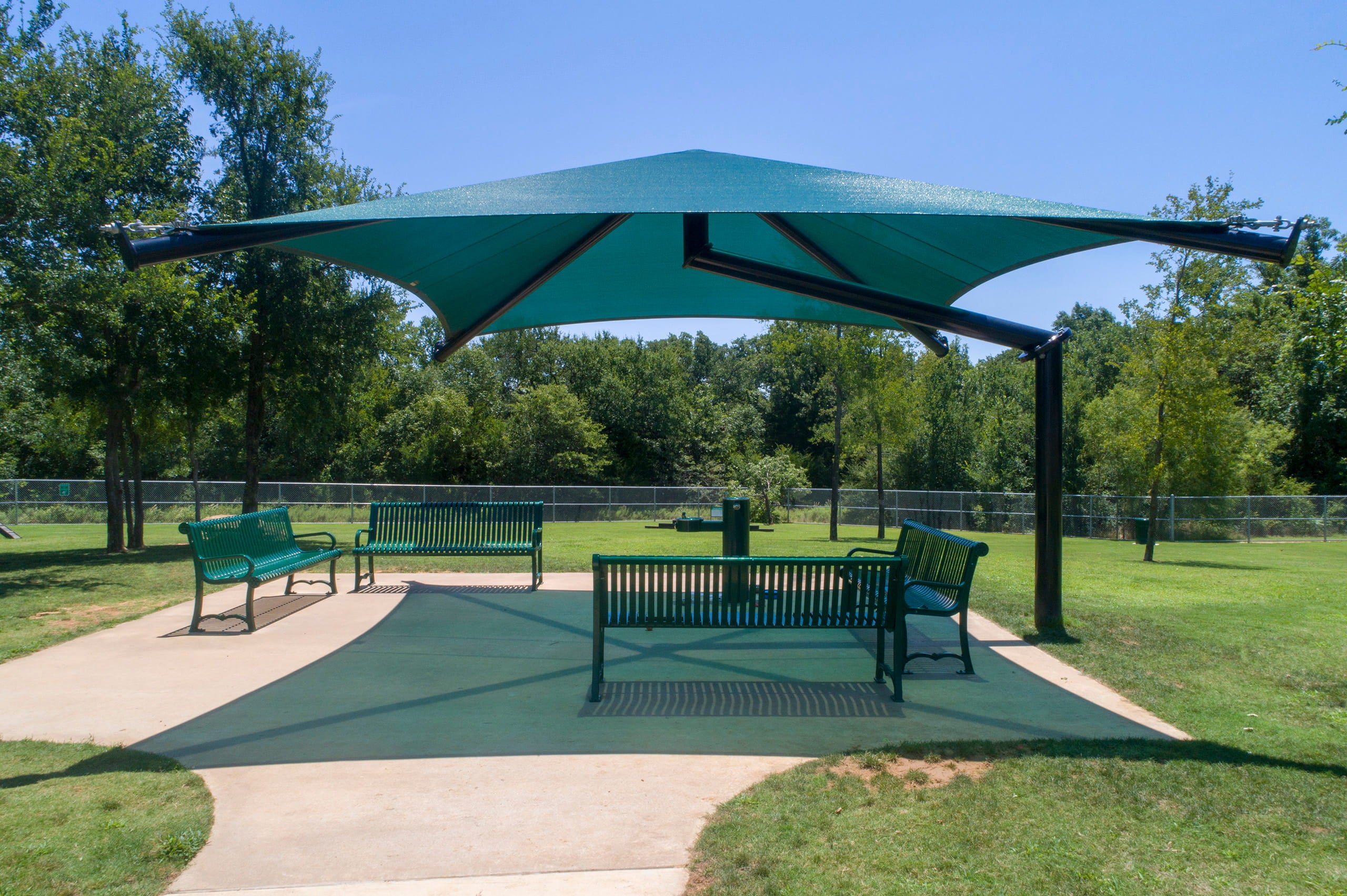 Green outdoor USA Shade Single Post Cantilever Shade Structure with benches in a park setting