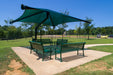 Green outdoor seating area with a large USA Shade Single Post Cantilever Shade Structure in a park setting