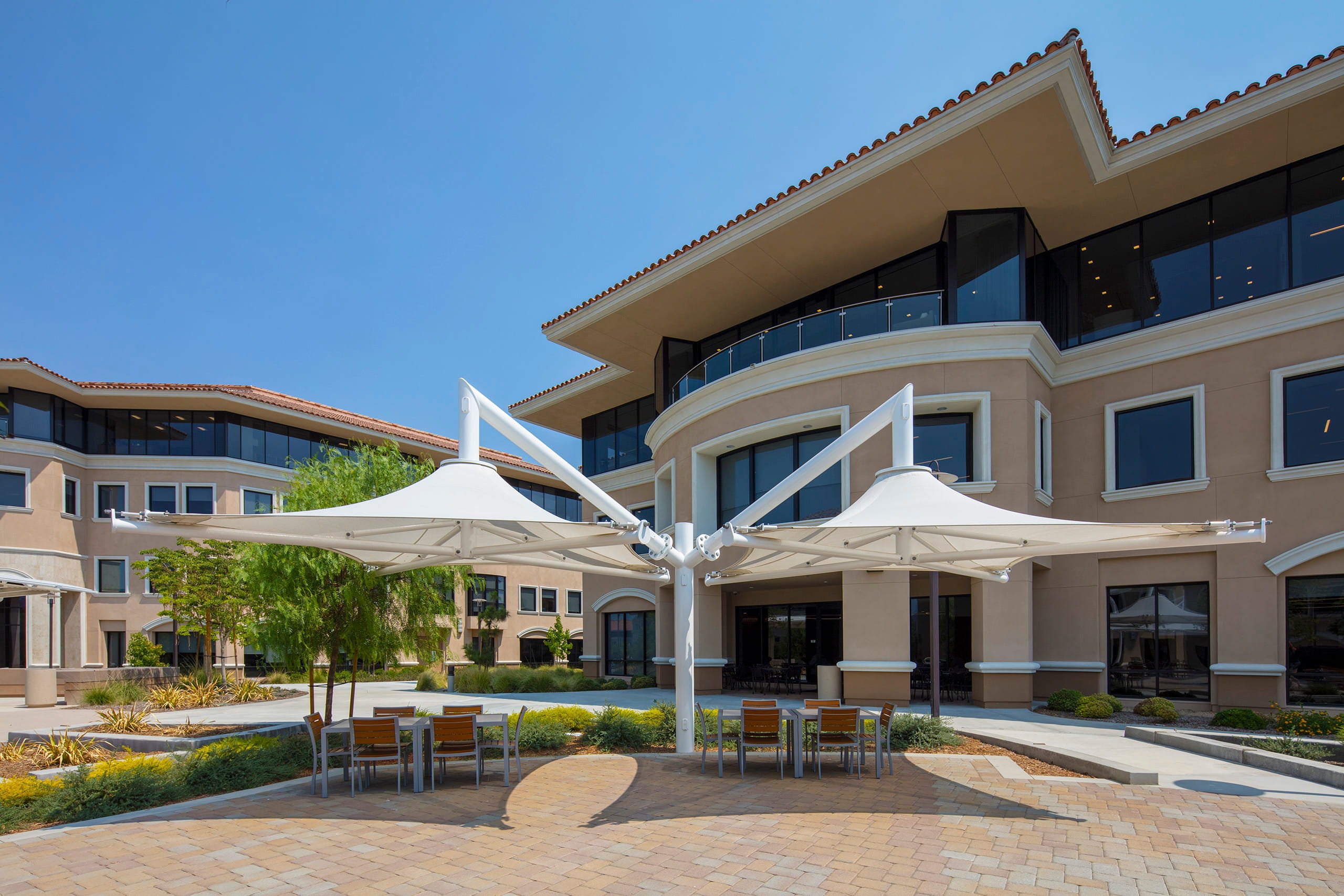 Outdoor seating area with tables and USA Shade Solana Cantilevers joined 4 in 1 in front of a building
