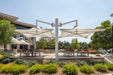 Outdoor seating area with large USA Shade Solana Cantilevers and tables in a park-like setting.