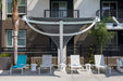 Outdoor patio area with lounge chairs and a large USA Shade Pegasus Shade in front of an apartment building.