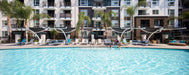 Pool area with lounge chairs and USA Shade Pegasus Shades in front of a multi-story apartment building.