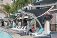 Poolside area with lounge chairs, USA Shade Pegasus Shades, and a person reading a book under.