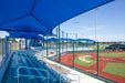 Baseball field with blue dugout and seating area under a clear sky and blue USA Shade Full Hip Cantilever Shades