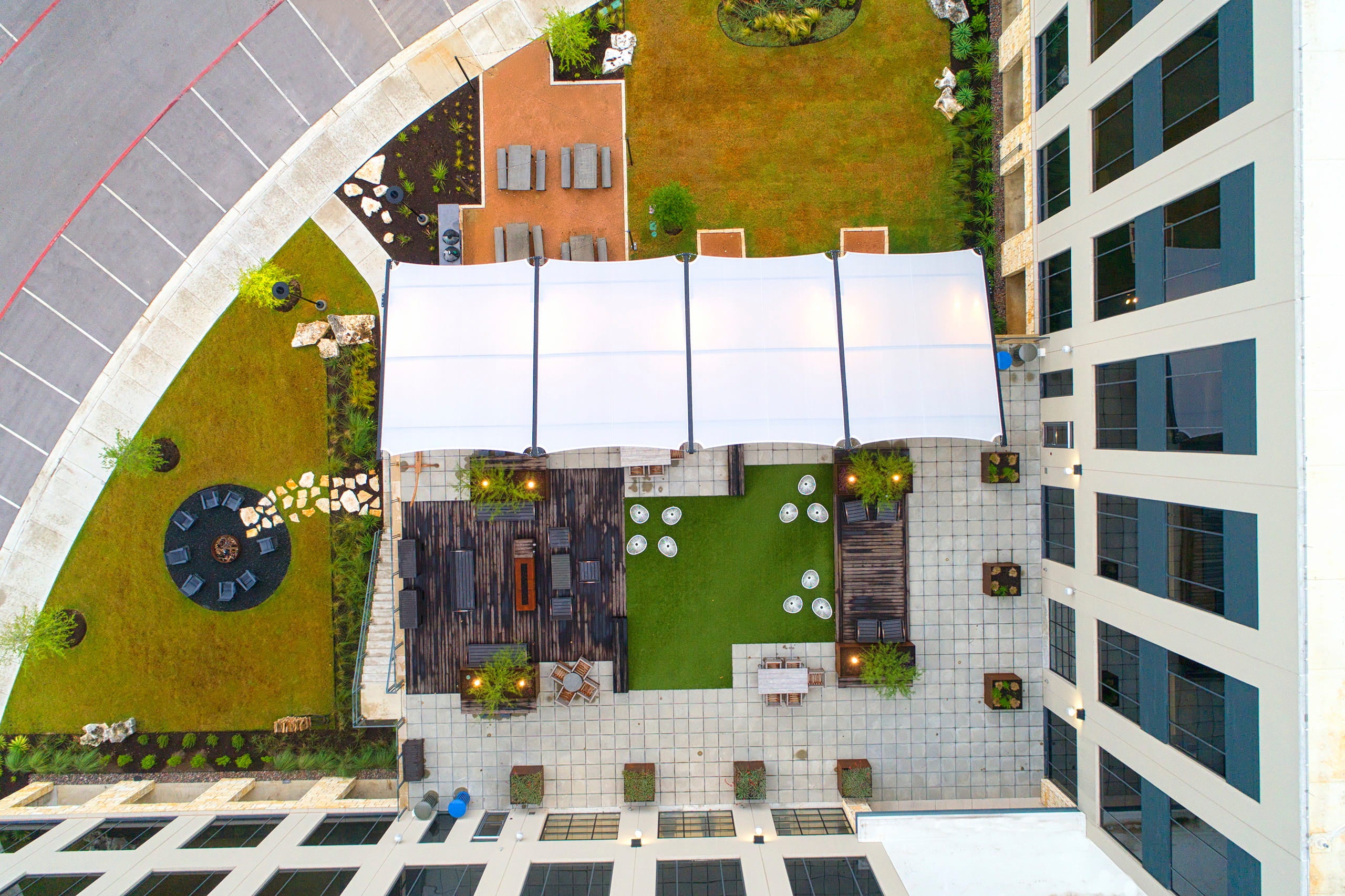 Top-down view of a building with a rooftop garden and outdoor area with a USA Shade Slanted Cantilever Cabled