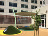 Children's playground area with green USA Shade Cantilever Disc shade and a building in the background