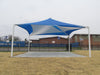 Blue and white USA Shade Mariner Pyramid Shade tent on a grassy area with a building in the background