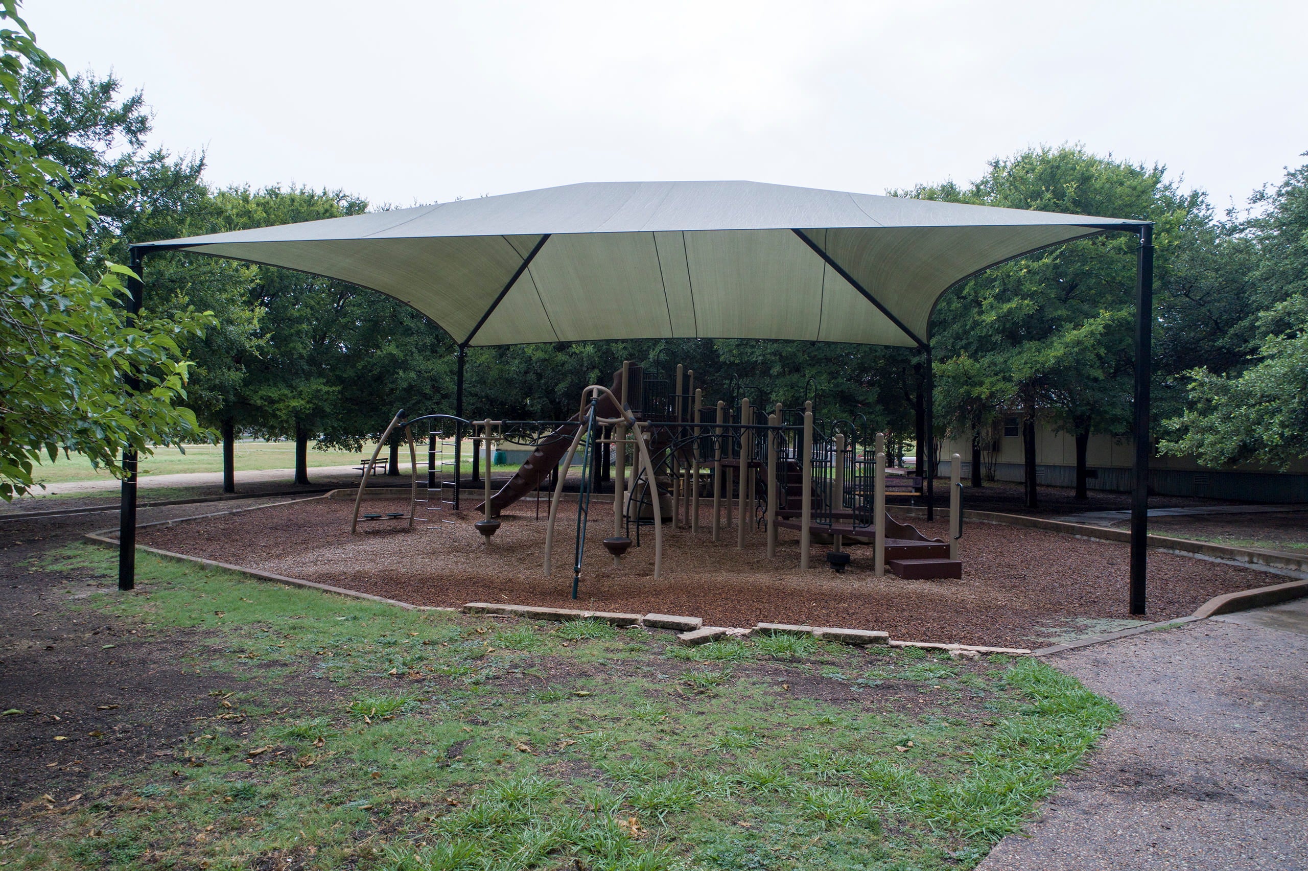 Outdoor playground with a large USA Shade Hip providing shade