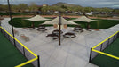 Outdoor sports facility with tennis courts and picnic tables under USA Shade Solana Cantilevers in a park setting.