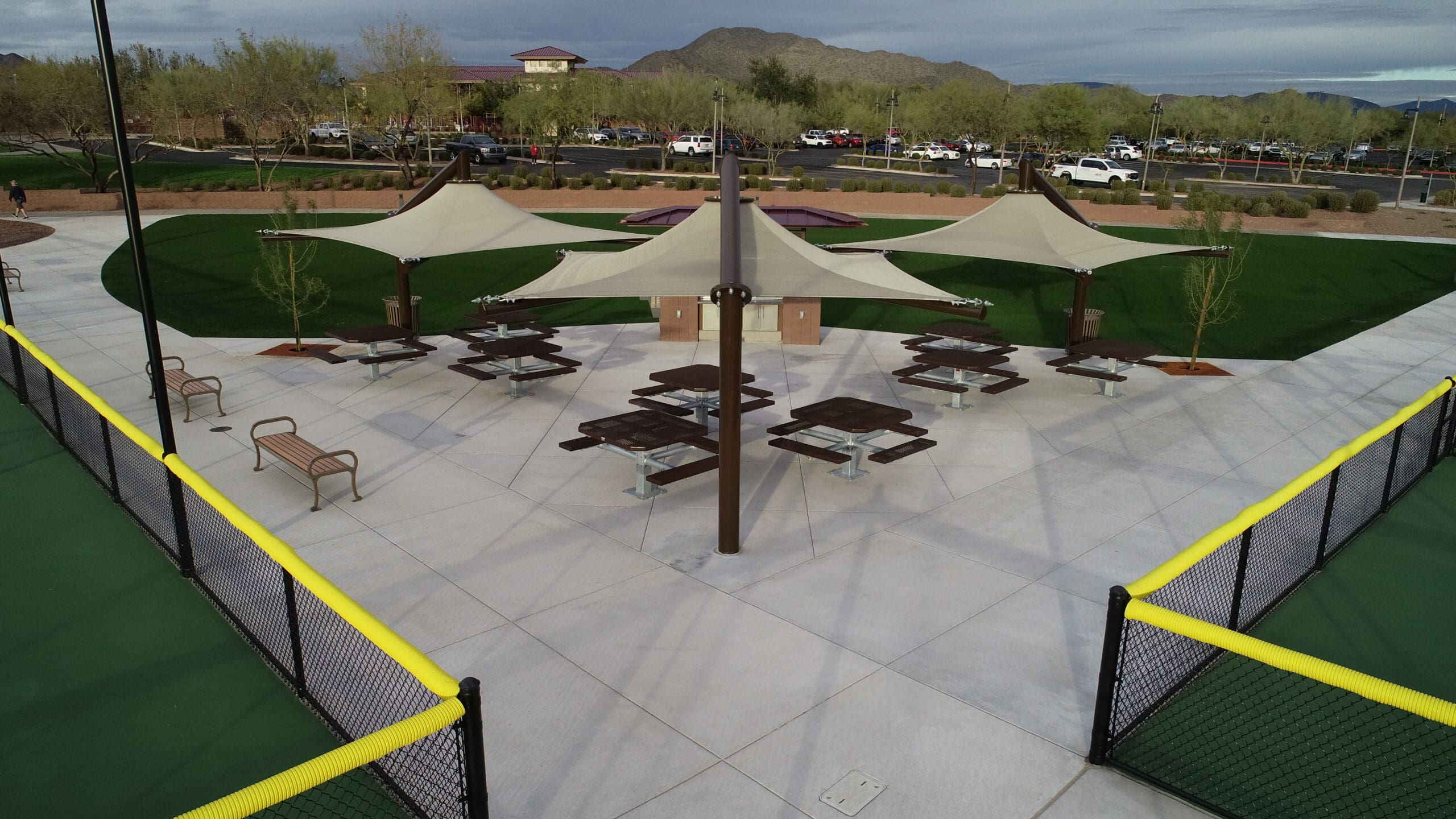 Outdoor sports facility with tennis courts and picnic tables under USA Shade Solana Cantilevers in a park setting.