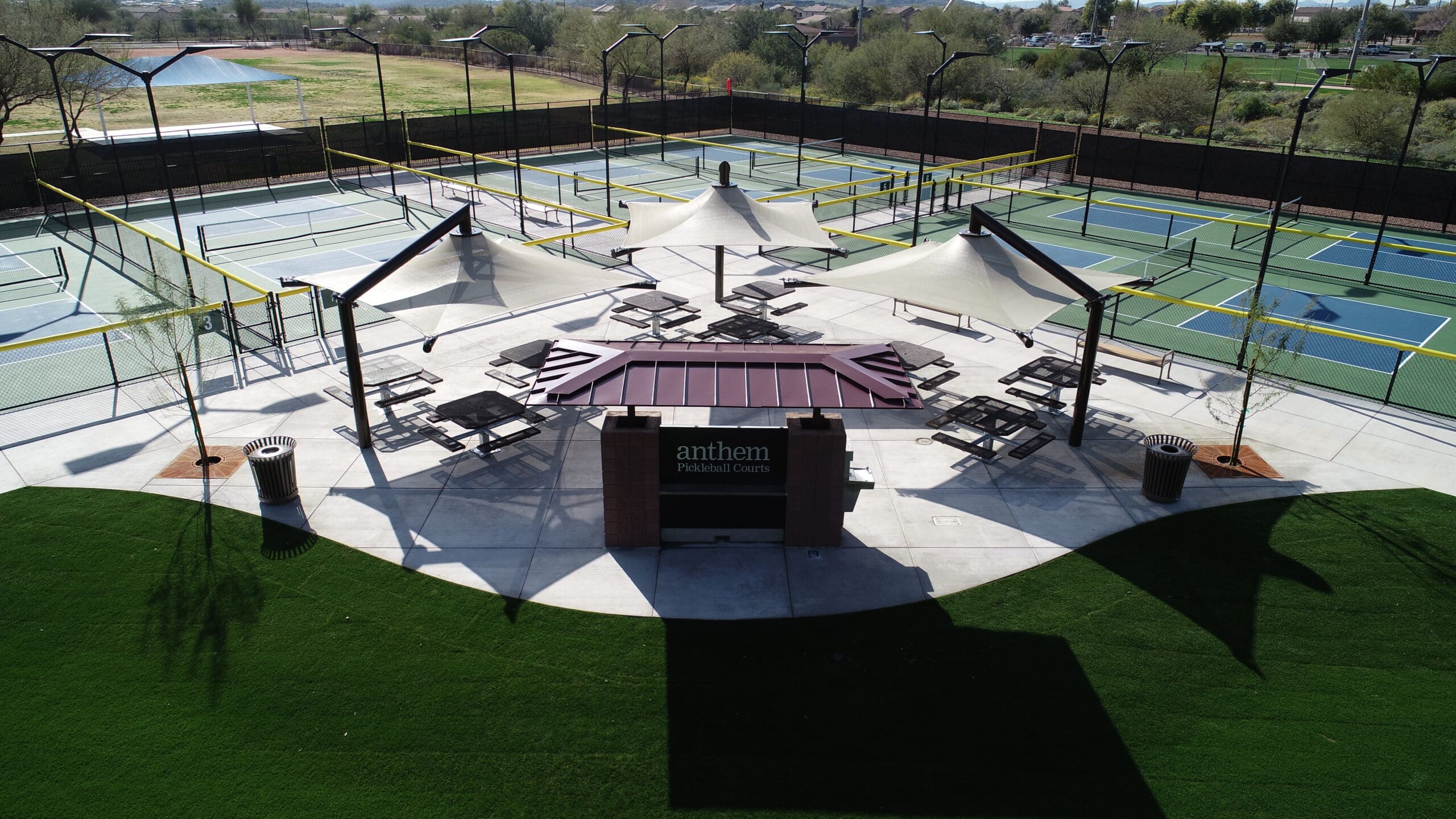 Outdoor pickleball courts with tables and chairs  under USA Shade Solana Cantilevers at a facility.