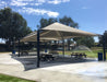 Large outdoor USA Shade Mariner Pyramid Shade providing shade over picnic tables in a park setting.