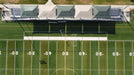 A football field with a stadium seating area covered by USA Shade Hips in the background