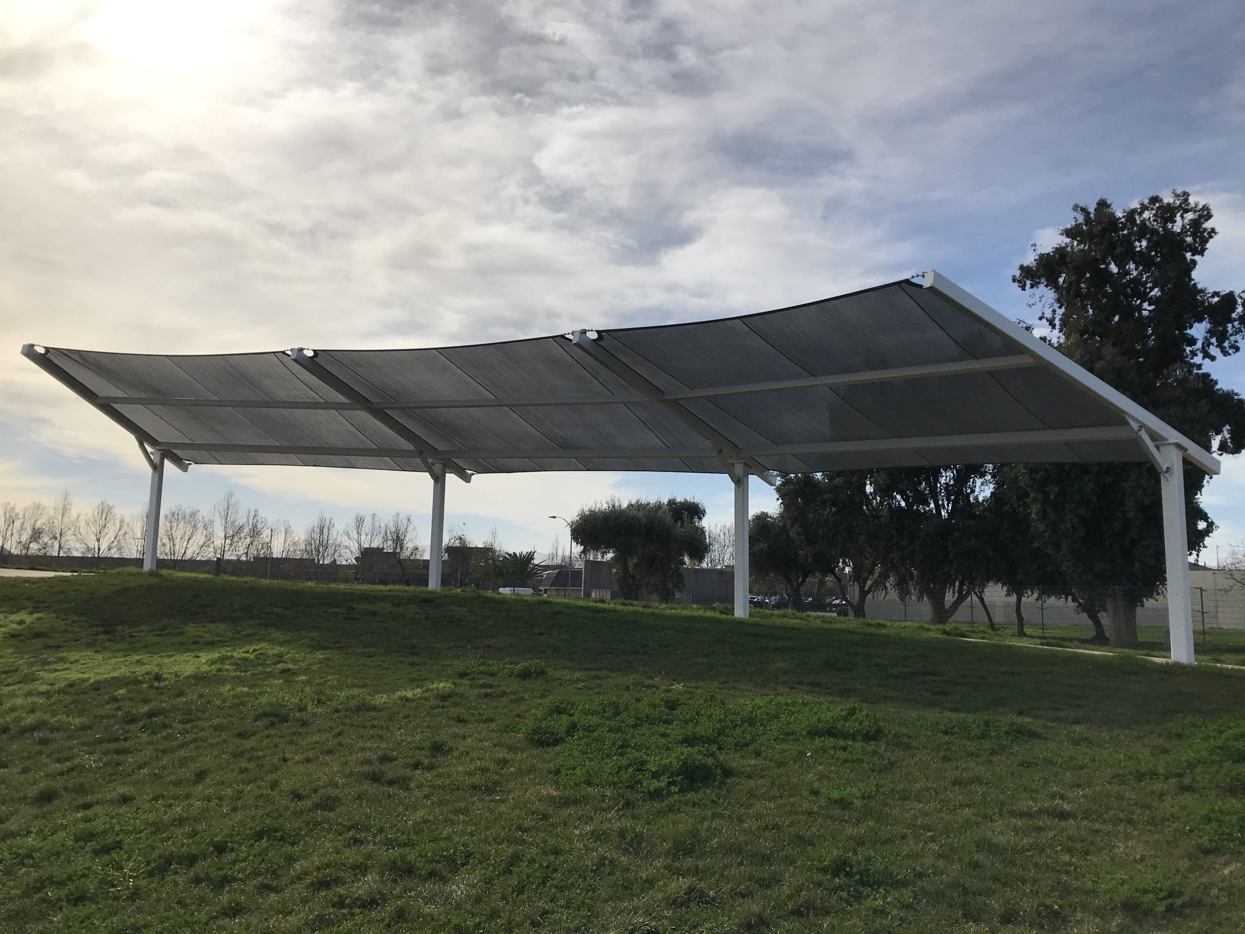 Solar panel USA Shade Slanted Cantilever Cabled structure in an outdoor setting with trees and grass.