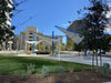 Modern outdoor USA Shade Aurora Shade with blue and white structure in a park setting with buildings in the background.