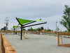 Outdoor area with green USA Shade Arbor Shade sails and wooden benches under a clear sky.