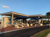 Outdoor seating area with tables and Blue USA Shade Single Post Pyramids at a park or recreational facility.