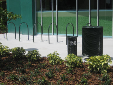 Black Wabash Valley Courtyard loop bike racks inground mounted along a campus sidewalk beside a perforated steel trash receptacle, school bike rack installation