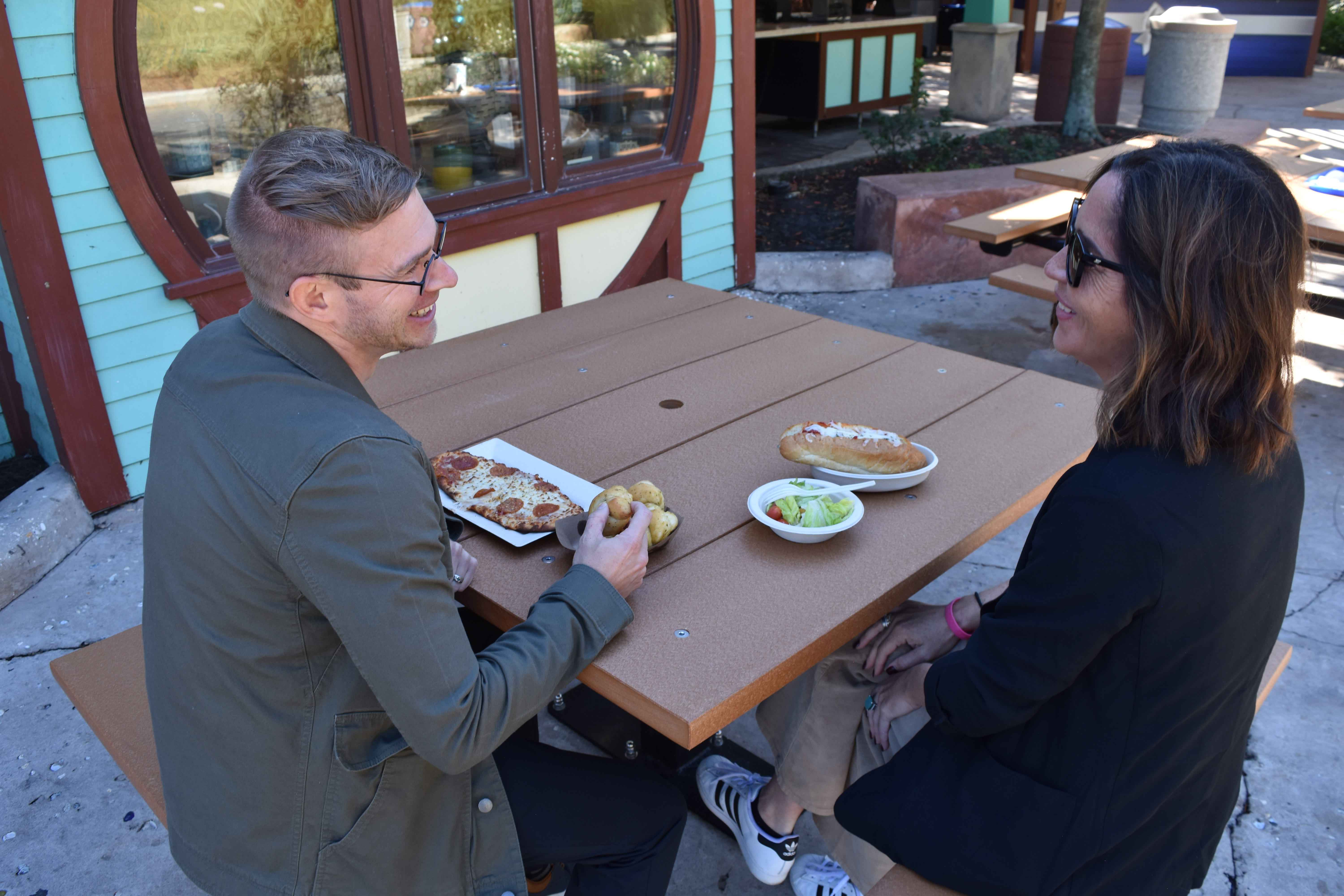 Two diners at a Black Wabash Valley Rinnova Square Picnic Table, Surface Mount, a commercial outdoor dining table